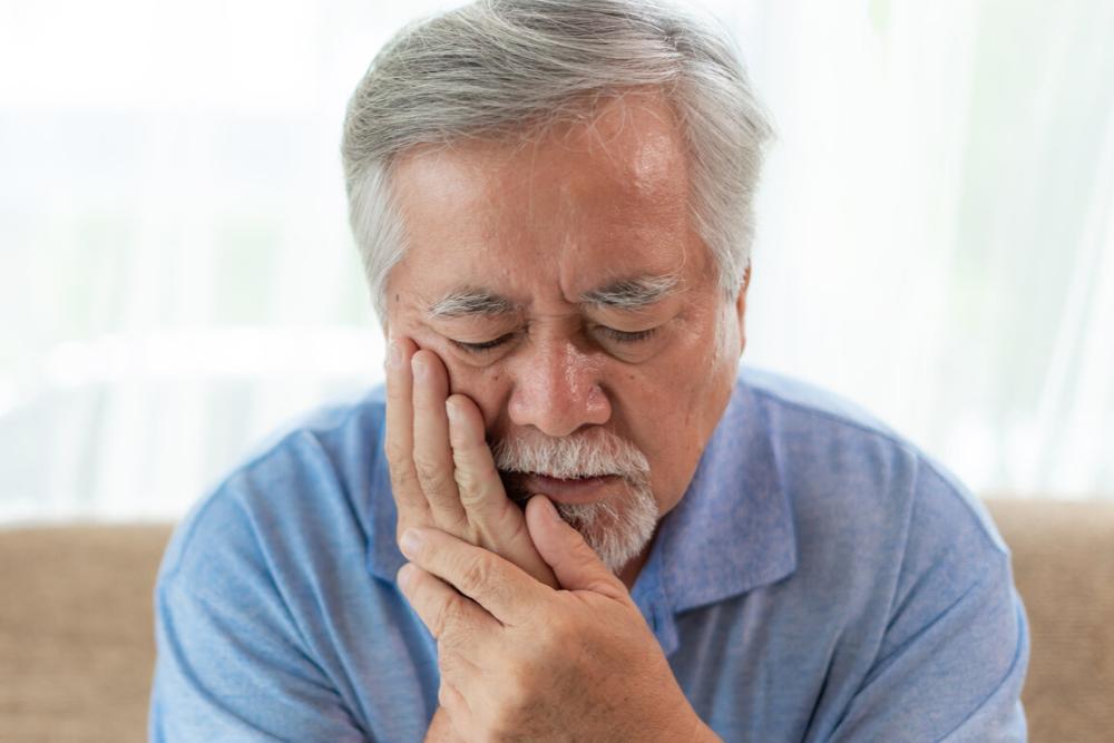 man holding jaw from tooth pain during a dental emergency in randolph