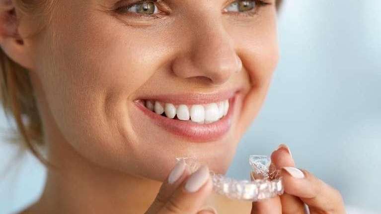 Lady holding Invisalign clear aligners at Randolph Dental Associates