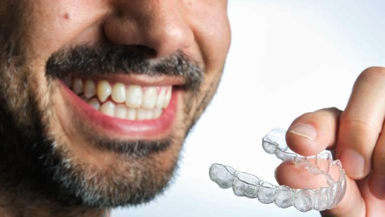 A man holding Invisalign clear aligners at Randolph Dental Associates