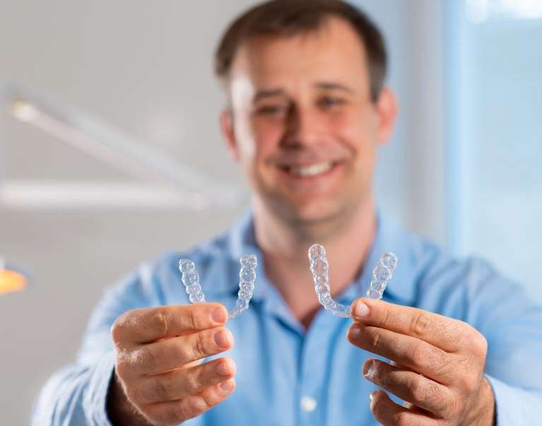 A man holding Invisalign clear aligners in Randolph NJ