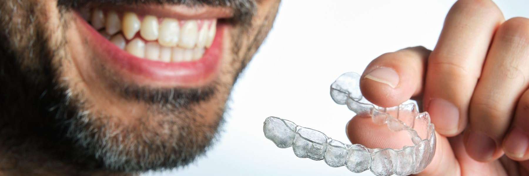 An image of a smile of a man holding clear aligners in Randolph, NJ