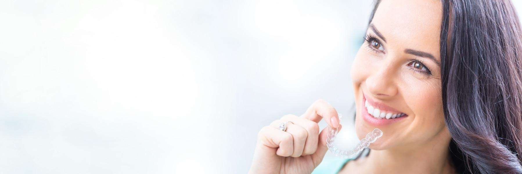 Lady holding Invisalign clear aligners at Randolph Dental Associates